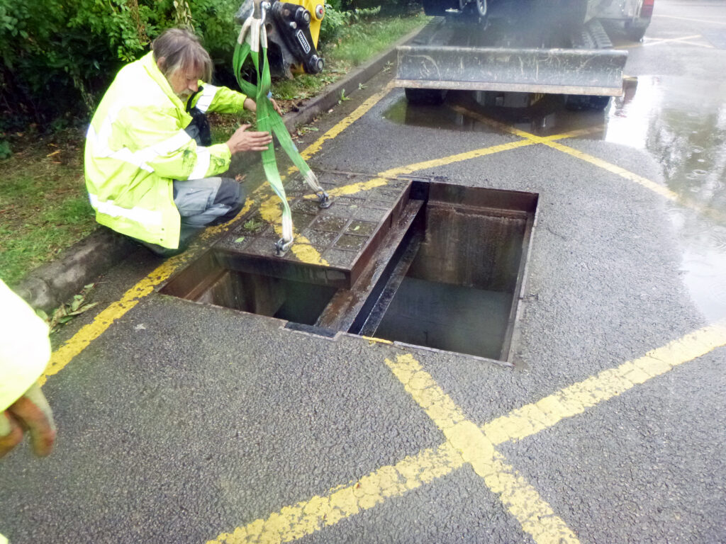 Corroded concrete infill covers being removed by a crane due to their weight